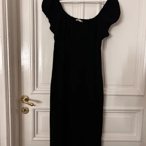 Svart klänning från Only - Snygg svart klänning från Only med korta puffärmar och en elegant, enkel design. Perfekt för en stilren look. Klänningen har en smickrande passform och är tillverkad i ett mjukt material.