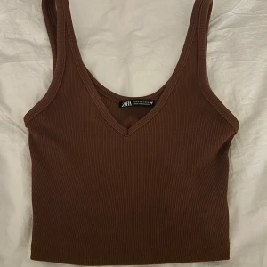 Brun ribbad linnetopp från Zara - Säljer en snygg brun ribbad linnetopp från Zara. Toppen har en v-ringad design.