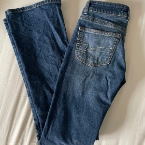 Blå jeans från Junkyard - Ett par mörkblå lågmidjade bootcut jeans ifrån junkyard, med detaljer på fickorna!⭐️Väldigt sparsamt använda, och i väldigt fint skick! Jag är ca 169cm lång och det sitter lagom i längden på mig! Normal i storleken.💕 Ordinare pris 599kr.