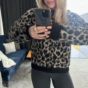 Leopardmönstrad tröja - Säljer en snygg leopardmönstrad tröja med långa ärmar. Tröjan har svarta muddar vid ärmslut och nederkant, vilket ger en fin kontrast till det djuriska mönstret. Perfekt för att liva upp garderoben!
