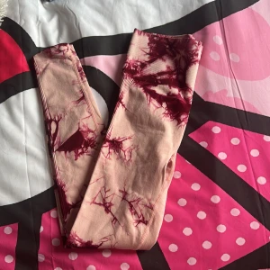 Beige och vinröda leggings - Snygga leggings i beige med vinrött batikmönster. Perfekta för en avslappnad stil med en unik touch. De är stretchiga och bekväma, vilket gör dem idealiska för både vardag och träning.