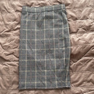 Rutig kjol från Holly & Whyte - Snygg rutig kjol (58 cm) från Holly & Whyte i en klassisk design. Kjolen har ett stilrent mönster i svart, vit och beige. Perfekt för en chic look.