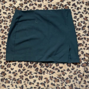 Svart kortkjol - Snygg svart kortkjol med en stilren design. Perfekt för att matcha med olika toppar och accessoarer. Kjolen har en liten slits på sidan som ger en extra touch till looken.