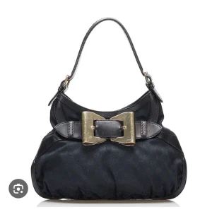 Svart Gucci axelväska med rosett - Sååå snygg svart axelväska från Gucci med en stor dekorativ rosett i guld på framsidan. Väldigt fint skick. Kom priv för fler bilder☺️ pris kan diskuteras