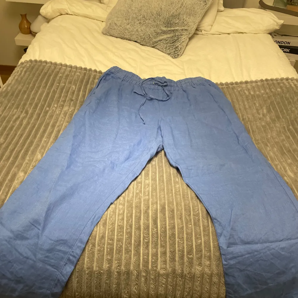 Säljer ett par bekväma blå linnebyxor med elastisk midja och snörning. Aldrig haft på mig den, storlek L från H&M. Farkut & Housut.