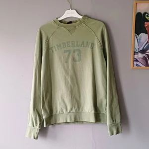 Vintage Timberland sweatshirt  - Säljer en grön sweatshirt från Timberland med tryck 'Timberland 73' på framsidan. Tröjan är tillverkad i 100% bomull.
