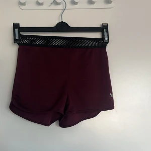 Vinröda träningsshorts från SOC - Snygga vinröda träningsshorts från SOC med elastisk midja och diskret logga. Perfekta för sport och aktivitet med en bekväm passform. Materialet är lätt och andas bra, vilket gör dem idealiska för intensiva träningspass.