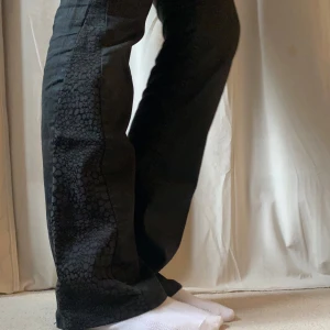 Lågmidjade jeans - Svarta Lågmidjade jeans som är omsydda till bootcut med coolt, mönstrat tyg! Är i fint skick! Skriv vid eventuella frågor. Pris går att diskutera🩷 Passar S och XS