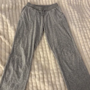Grå mjukisbyxor från Juicy Couture - Säljer ett par grå mjukisbyxor från Juicy Couture med broderad logga på benet. Byxorna har en bekväm resårmidja med snörning och praktiska fickor både fram och bak. Perfekta för en avslappnad stil. Priset kan diskuteras. (Knappt använda) 
