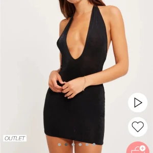 Svart axelbandslös klänning från Nelly - Trendig svart axelbandslös klänning med djup v-ringning och knytning i nacken. Perfekt för en utekväll med sin korta längd och eleganta design.