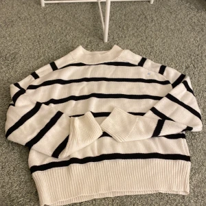 Randig stickad tröja från Amisu - Säljer en snygg randig stickad tröja från Amisu i svart och vitt. Tröjan har långa ärmar och en klassisk rund halsringning. Har en liten blå fläck uppe i vänstra axeln. Jag tror att den går att få bort men därav priset! Köpte för 399