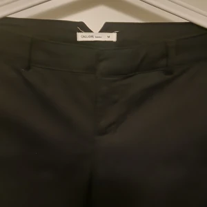 Svarta byxor från Calliope - Snygga svarta byxor från Calliope i storlek M. De har en klassisk design med en rak passform och är perfekta för en stilren look. Byxorna är tillverkade i ett bekvämt material som passar till många olika tillfällen.