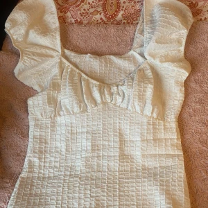 Vit blus med volangdetaljer - Säljer en söt vit blus med volangdetaljer från Primark. Aldrig använda