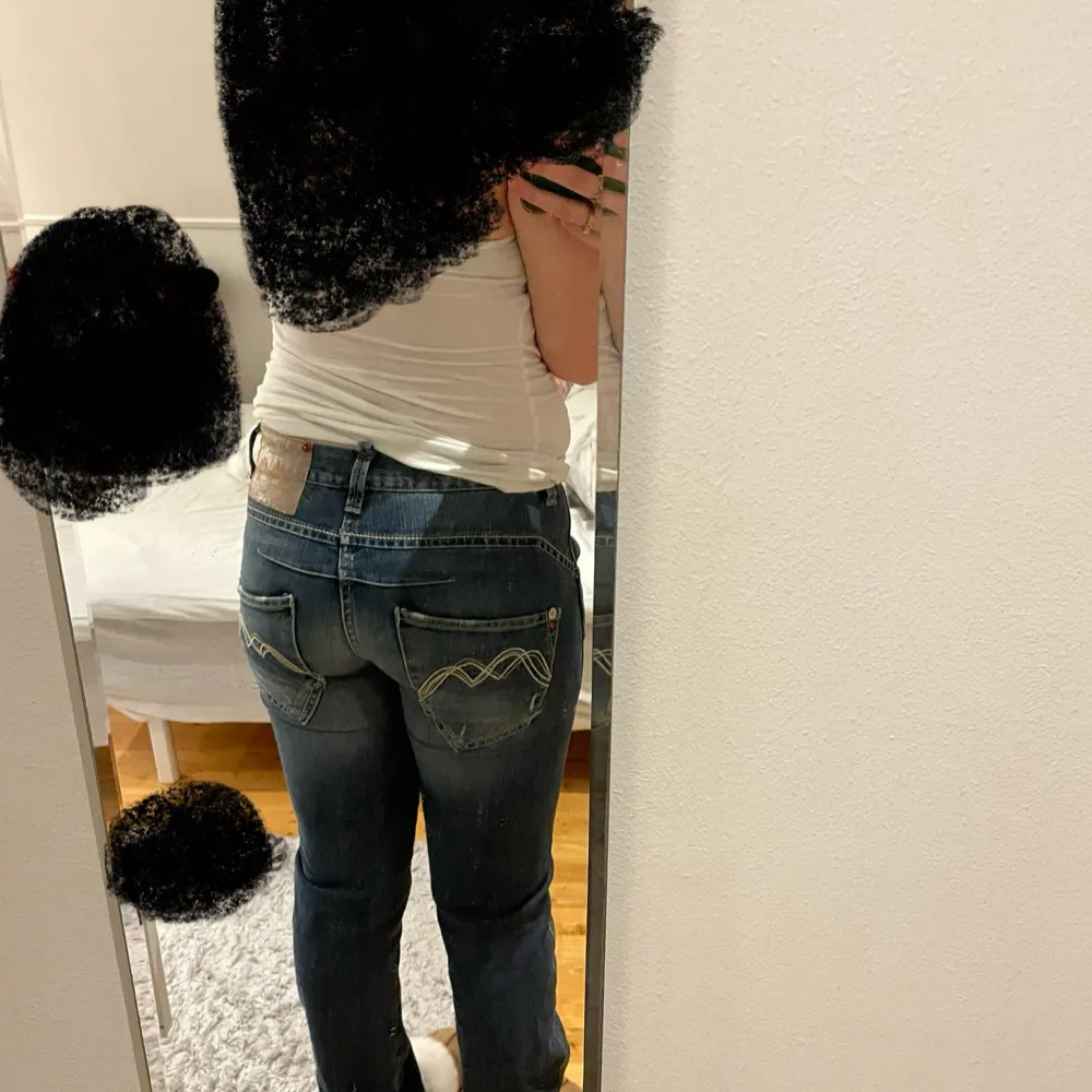 Snygga blåa lågmidjade jeans med unika broderade detaljer på bakfickorna. De har en lågmidjad passform och knappar i olika färger framtill. Köpta någon stans i Cypern, använder inte längre därför jag säljer. Skulle säga att dom är i storlek S ungefär (det står ingen storlek). Farkut & Housut.