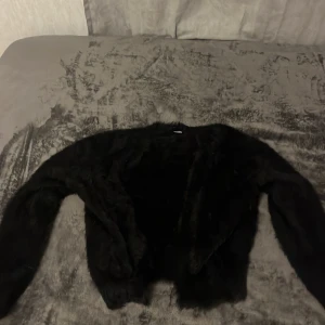 Svart pälsjacka från H&M Divided - Säljer en svart pälsjacka från H&M Divided i storlek XS. Jackan har en mjuk och fluffig textur, perfekt för att hålla dig varm och stilren under kyliga dagar. Den har långa ärmar och en öppen design utan knappar eller dragkedja.