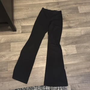 Svarta byxor från H&M Divided - Snygga svarta byxor från H&M Divided i en klassisk bootcut-stil. Perfekta för en stilren look med en bekväm passform. Byxorna är tillverkade i ett mjukt material som ger en skön känsla hela dagen.