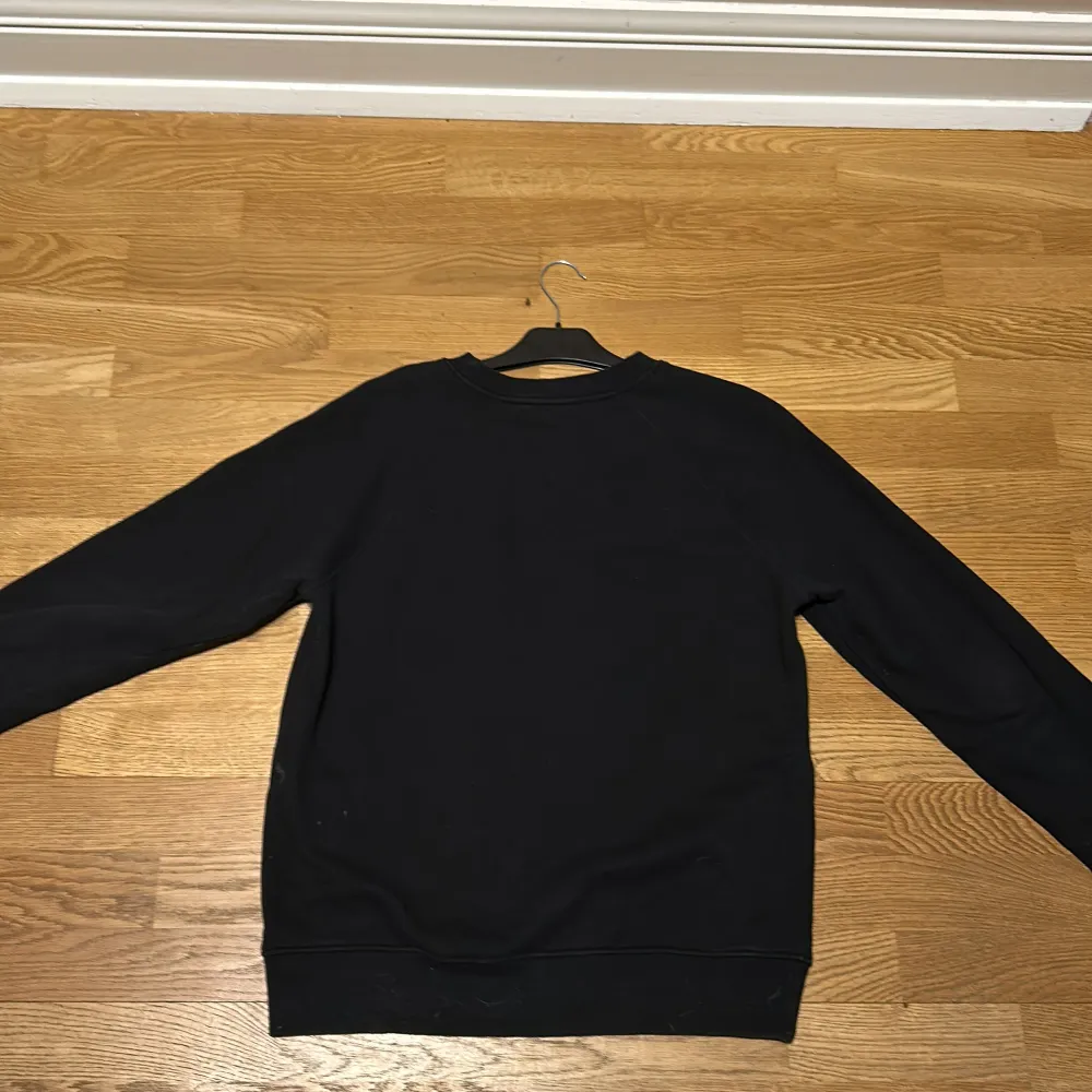 Säljer en stilren svart sweatshirt från Balmain med deras ikoniska logga tryckt på framsidan. Tröjan är tillverkad i mjuk bomull och har långa ärmar samt ribbade muddar vid ärmslut och nederkant. Perfekt för en casual look. Skick: 9/10 (använd fåtal gånger). Priset går att diskutera!. Neuletakit & Villapaidat.