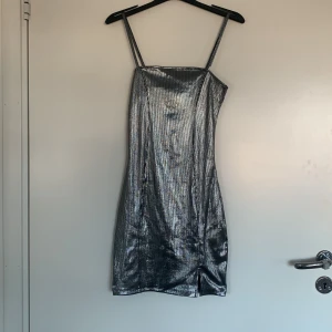 Glittrig silverklänning från H&M Divided - Snygg glittrig silverklänning från H&M Divided med smala axelband och en figurnära passform. Perfekt för en kväll ute med vänner. Materialet har en ribbad struktur som ger en extra touch till looken. ✨