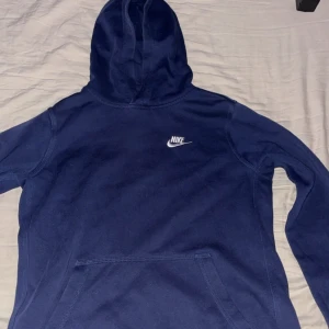 Mörkblå hoodie från Nike - Säljer en mörkblå hoodie från Nike med klassisk logga på bröstet. Tröjan har en stor huva och en praktisk magficka 