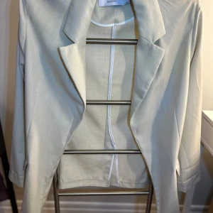 Beige kavaj från Bershka - Snygg beige kavaj från Bershka i storlek L. Kavajen har en klassisk design med långa ärmar och en stilren krage. Perfekt för att ge en elegant touch till din outfit. Tillverkad i ett lätt och bekvämt material.