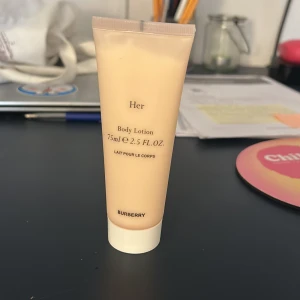 Body Lotion Her från Burberry - Säljer en lyxig body lotion från Burberry, 'Her', i en smidig 75 ml tub. Den har en elegant beige färg och är perfekt för att återfukta huden. Tuben är lätt att använda med en praktisk skruvkork. Perfekt för att ta med på resan eller ha i handväskan.