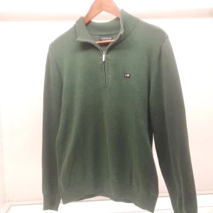 Grön tröja med dragkedja från Lexington - Säljer en stilren grön tröja från Lexington med halv dragkedja och ribbad krage. Tröjan har en liten Lexington-logga på bröstet och är perfekt för kyligare dagar. Passar både till vardags och mer avslappnade tillfällen.pris kan diskuteras