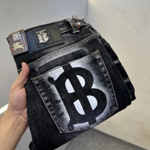 Svarta jeans med burberry tryck - Coola svarta jeans med ett stort burberry tryck på bakfickan. Jeansen har en unik design med en blekt effekt runt trycket. Perfekta för en trendig look.