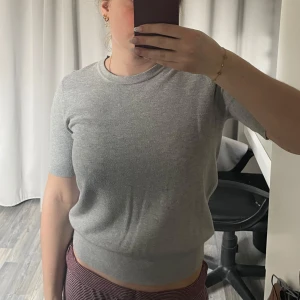 Grå tröja från Zara - Säljer en stilren grå tröja från Zara. Tröjan har en rund halsringning och korta ärmar, perfekt för en avslappnad look. Materialet känns väldigt mjukt och bekvämt mot huden. Det är storlek L men passar perfekt på mig som vanligtvis använder Xs och S🩶