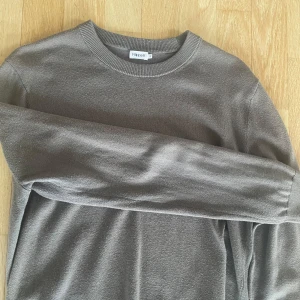 Grå/grön tröja från Filippa K - Säljer en stilren grå tröja från Filippa K i storlek S. Tröjan har en klassisk rund halsringning och långa ärmar. Perfekt för en minimalistisk garderob. Tillverkad i ull material. Skick 9/10