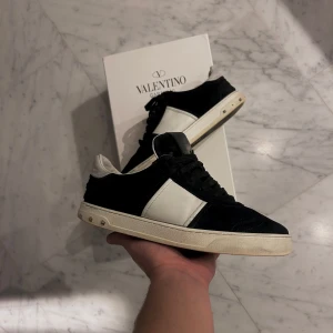 Valentino sneakers i svart och vit - Snygga Valentino flycrews i svart och vit! Skorna har ett bra skick men några nitar som låssnat! Sulan har ett unikt mönster och små nitar på sidan! Storleken är 40 men passar mig som har 41,5 i andra designerskor som till exempel lanvin!  Box medföljer! Samt extra snöring mm. Skriv vid intresse! Priset är inte hugget i sten👏🏻👟