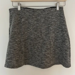 Grå kjol - Snygg grå kjol i melerat tyg med en klassisk och stilren design. Perfekt för en chic och enkel look. Elastisk i midjan.