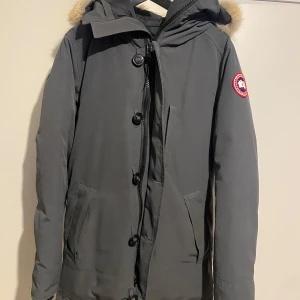  Canada Goose chetau prarka grå - Säljer en stilren grå parkajacka från Canada Goose med pälsdetaljer på huvan. Jackan har både dragkedja och knappar framtill samt praktiska fickor. Nypris 17.700 kr. Perfekt för kalla dagar. Har även en avtagbar päls som jag tagit väl hand om. Självklart äkta. Först till kvarn! Kom med bud priset är ej hugget i sten