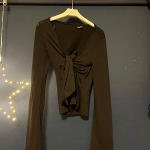 Svart långärmad topp med knyt - Snygg svart långärmad topp från H&M med knyt framtill. Perfekt för en stilren look.