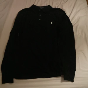 Svart pikétröja från Ralph Lauren - Snygg svart pikétröja från Ralph Lauren i slim fit. Perfekt för en stilren look. Size M men skulle passa på både de med M och S i storlek, vid funderingar är det bara att skriva! 