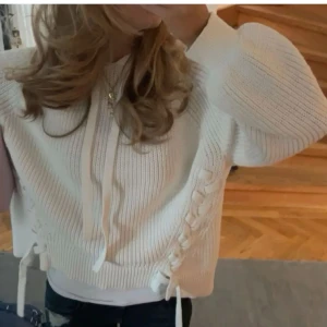 Vit stickad hoodie med snörning - snygg vit stickad hoodie med snörning på sidorna och jättefin passform . Tröjan har långa ärmar och en mysig huva med dragsko💗