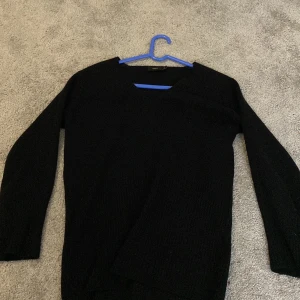 Svart tröja med V-ringning - Säljer en stilren svart tröja med V-ringning. Perfekt för både vardag och mer uppklädda tillfällen. Tröjan har långa ärmar och är tillverkad i ett mjukt material som ger en bekväm passform.