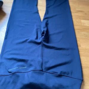 BUDA: Mörkblå träningsleggings med dragkedja och flared ending - Snygga mörkblå leggings perfekta för träning. De har en praktisk dragkedja och är tillverkade i ett snabbtorkande material. Perfekta för en aktiv livsstil!