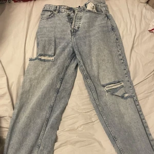 Fyra par byxor i olika stilar och färger - Säljer fyra par byxor: ljusblå jeans med slitningar, svarta byxor med bootcut-stil, ljusblå jeans med graffiti-mönster och bruna byxor med bootcut-stil. Dem blåa jeansen är i väldigt bra skick, de andra två är lite mer använda men fortfarande bra skick! En för 60kr alla för 200kr