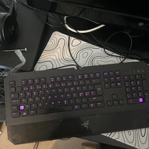 Razer DeathStalker Chroma tangentbord - Säljer ett Razer DeathStalker Chroma tangentbord med justerbar RGB-belysning. Tangentbordet har en slimmad design och är perfekt för gaming. Det är utrustat med chiclet-tangenter och en bekväm handledsstöd. Ansluts via USB.