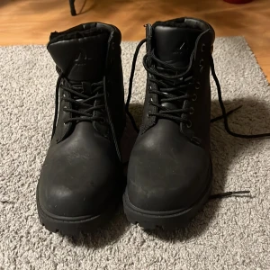 Svarta boots från McKinley - Säljer ett par svarta boots från McKinley, modell Tirano NB II. Skorna har snörning och är tillverkade i syntetmaterial. Perfekta för kyligare väder med sin robusta design.