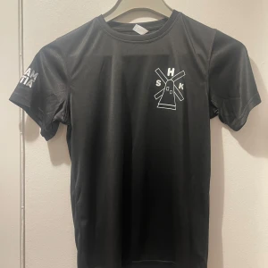 Svart t-shirt med tryck - Snygg svart t-shirt med ett stilrent vitt tryck av en väderkvarn på bröstet. Kortärmad design med rund halsringning. Perfekt för en avslappnad stil.