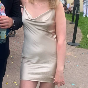 Champagnefärgad sidenklänning - Elegant champagnefärgad kortklänning i siden med smala axelband och draperad halsringning. Använd en gång.