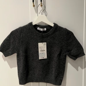 Mörkgrå stickad tröja från Zara - Snygg mörkgrå stickad tröja från Zara XS. Toppen har korta ärmar och är lite kortare i modellen🩶Nyskick med lappen kvar!