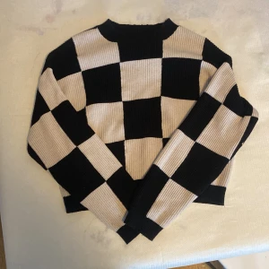 Svart och vit rutig tröja från MNG - Säljer en snygg svart och vit rutig tröja från MNG. Tröjan har ett iögonfallande schackrutigt mönster och är ribbad för extra stil. Perfekt för att ge din garderob en trendig touch!