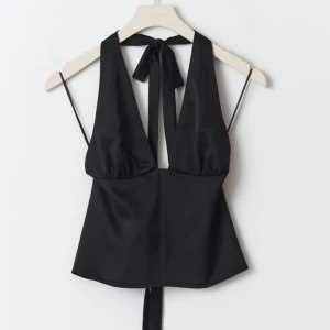 Svart halterneck topp - Helt oanvänd, prislappen kvar! Nypris 360kr. Snygg svart halterneck topp med djup urringning och knytband i nacken. Toppen har en öppen rygg och smala axelband, perfekt för en kväll ute.
