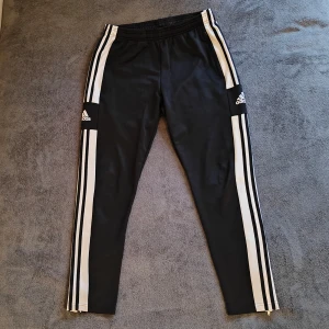 Adidas träningsbyxor  - Svarta träningsbyxor från Adidas. Byxorna har dragkedjor vid bensluten för extra komfort så att man kan vädra. Perfekta för träning eller en avslappnad stil. Storlek small och material av 100% polyester. Kontakta för frågor eller fler bilder!