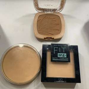 Puder och bronzer från L'Oréal och Maybelline - Säljer ett set med puder och bronzer. Inkluderar L'Oréal Bronze to Paradise och Maybelline Fit Me Matte + Poreless i nyans 120 och Rimmel puder i 006 Warm beige. Perfekt för en matt och jämn finish.
