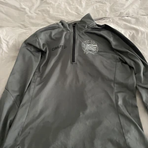 Limited edition Bajen tröja - Limited edition Bajen tröja. Säljer en grå långärmad tröja från Craft med dragkedja vid halsen. Perfekt för träning eller som ett extra lager under kalla dagar. Tröjan har en stilren design med Craft-logga på bröstet.