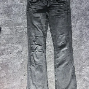 Grå jeans med bootcut, Gina Tricot - Snygga grå jeans med bootcut-stil, låg midja och klassiska femficksdetaljer. De har en knapp och dragkedja framtill och snygga detaljer såsom knappar på baksida ficka. Storlek 164. Från Gina Tricot. 