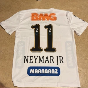 Neymar santos tröja - Vit kortärmad fotbollströja från Nike med tryck av nummer 11 och Neymar Jr på ryggen. Sponsorer som BMG och Marabraz är tryckta på framsidan och ärmarna. Perfekt för fotbollsfans!